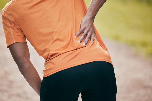 Photo ive put something out again. cropped shot of an unrecognisable man standing alone and suffering from backache during his outdoor workout.