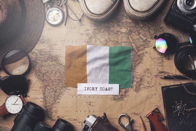 Ivory Coast Flag Between Traveler's Accessories on Old Vintage Map. Overhead Shot