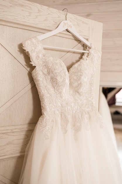 Ivory lace wedding long dress hanging on a wooden hanger