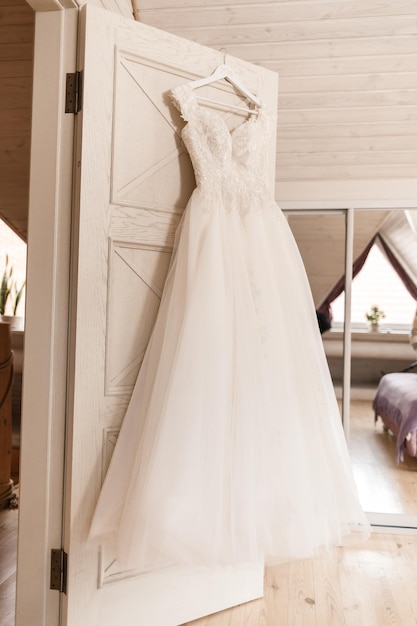 Ivory lace wedding long dress hanging on a wooden hanger