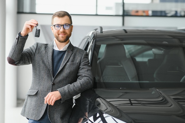 Ja, dat is mijn nieuwe auto Klant in autodealer Jonge man knielde neer met sleutels in de hand