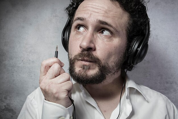 Photo jack, listening and enjoying music with headphones, man in white shirt with funny expressions