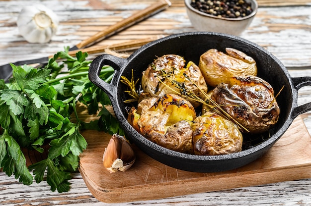 Jacket baked potato with garlic and rosemary in a pan. White background. Top view.