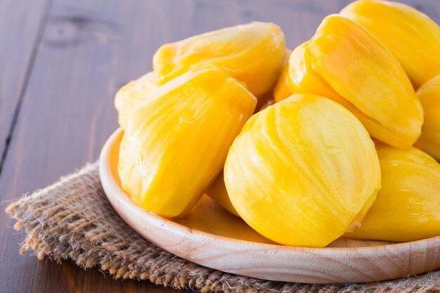 Jackfruit ha cucinato su un piatto che è fatto di legno e disposto su un pavimento di legno.