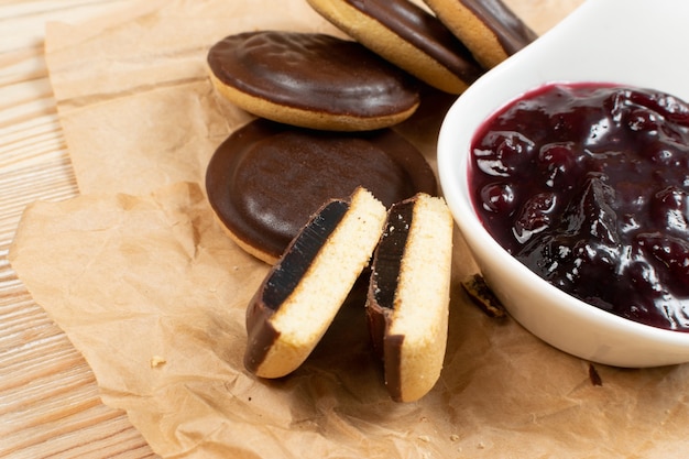 Jaffa cake or biscuit cookie filled with natural jam. Round chocolate covered cookies with fruit marmalade or jelly on wood table background