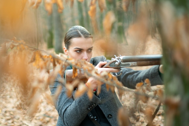 Foto jager die bos observeert. vrouwelijke jager in bos. succesvolle jacht. jacht sport. vrouw met wapen. doel schot. militaire mode. verwezenlijkingen van doelen. meisje met geweer. jagen jagen. wapenwinkel