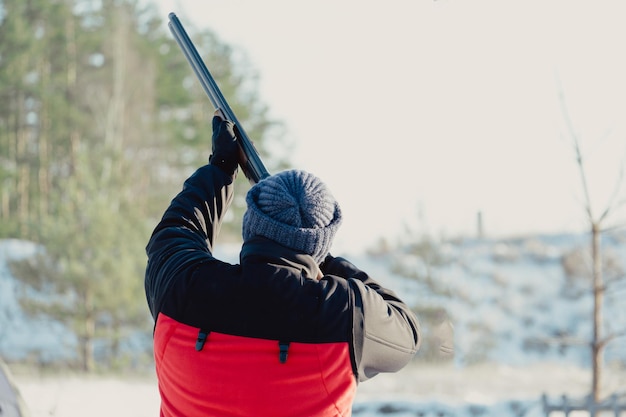 Jager in camouflage met geweer in winterbos. Jacht concept. Man die een reserve beveiligt, op een besneeuwde dag. Hunter richt met een geweer in het besneeuwde bos