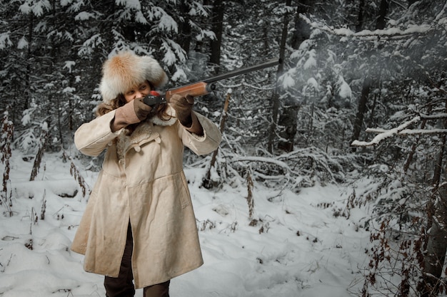 Jager in de winter vintage kleding schiet pistool in het bos