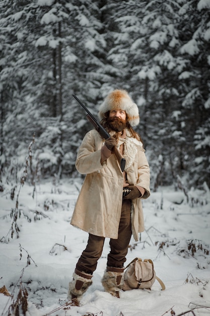 Jager in vintage kleding met pistool sluipt door bos