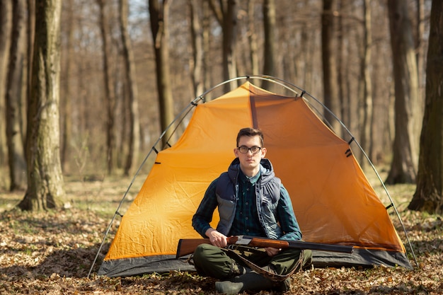 Jager met een geweer in het bos dat bij de tent zit