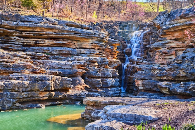 Jagged rocks featuring simple waterfall into teal waters