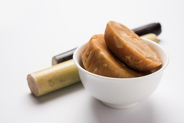 Jaggery OR Gur with Sugar Cane over moody background. Selective focus