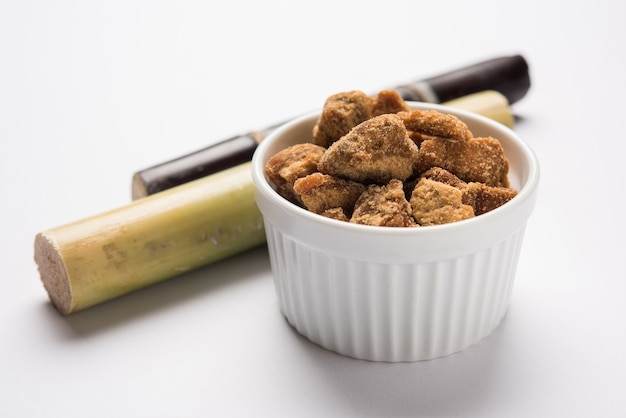 Foto jaggery o gur con la canna da zucchero su sfondo lunatico. messa a fuoco selettiva