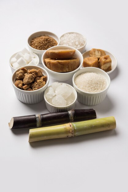 Jaggery, Sugar Variety 및 Sugarcane - 사탕수수 또는 Ganna의 부산물은 변덕스러운 배경 위에 배치됩니다. 선택적 초점