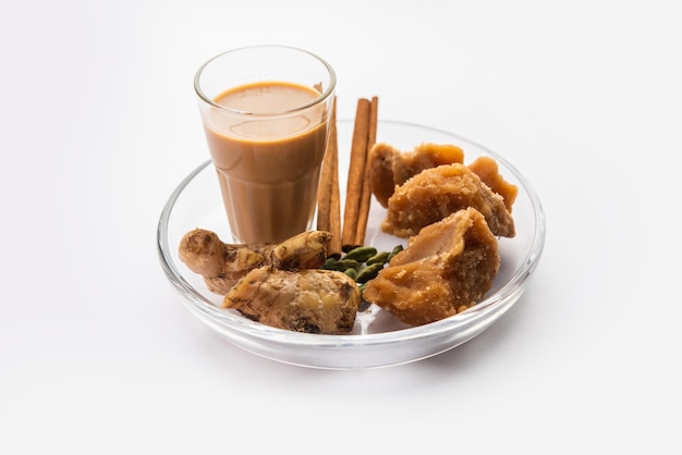Photo jaggery tea or gur ki chai with ingredients like gud ginger or adrak green cardamom and cinnamon