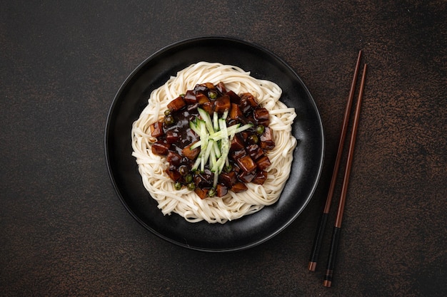 Jajangmyeon, корейская лапша в соусе из черной фасоли на темном фоне, вид сверху