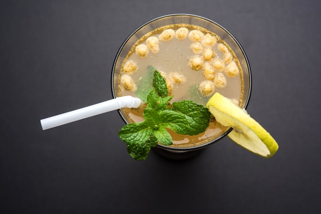 Jal-Jeera OR Jaljira is an Indian beverage prepared using mixing cumin powder in water and served cold with Boondi, Mint and Lemon slice. Served over moody background. Selective focus