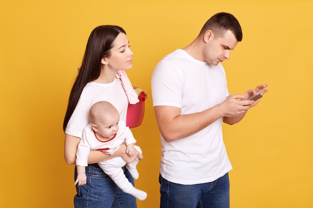 Jaloerse nieuwsgierige vrouw die echtgenoot bespioneert en zijn mobiele telefoon bekijkt terwijl hij achter zijn rug staat