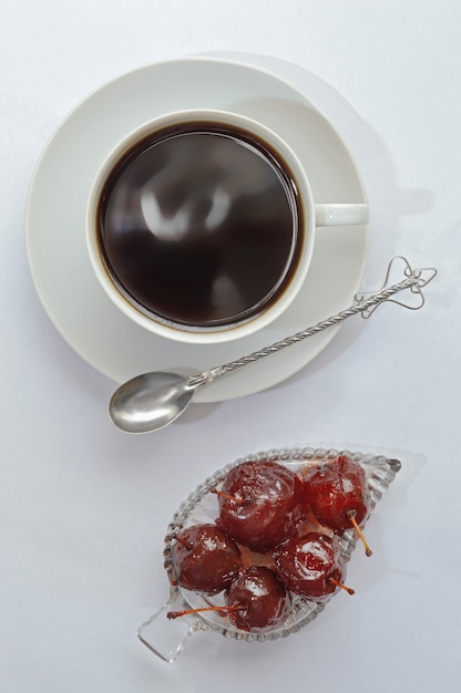 Jam in a bowl, a cup on a saucer and a spoon..