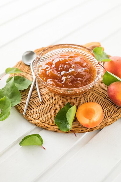 Marmellata di albicocche e albicocche fresche sullo sfondo di legno