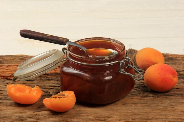 Jam from apricots in a glass jar on an old wooden surface board