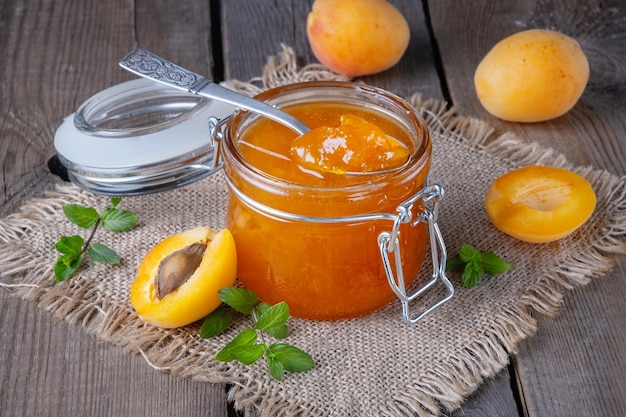 Jam from apricots in a glass jar on an old wooden table