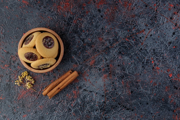 Jam-ringkoekje in een kleikom met kaneelstokjes en mimosabloem