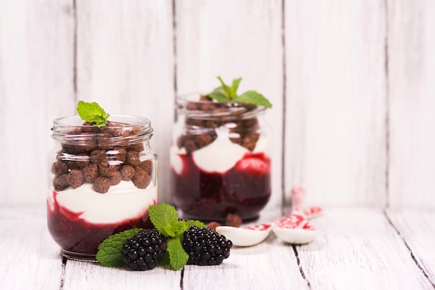 jam, yoghurt en chocolade ballen in glazen potten, geserveerd met bramen en munt.