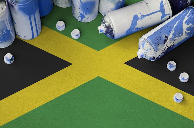 Jamaica flag and few used aerosol spray cans for graffiti\
painting street art culture concept