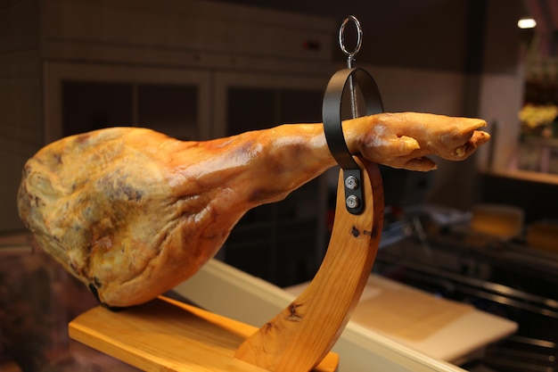 Foto prosciutto serrano. prosciutto spagnolo jamon - gamba intera di carne di maiale essiccata su un supporto di legno. jamon in piedi.