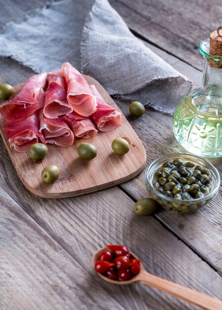 Jamon with capers and olives on the wooden board