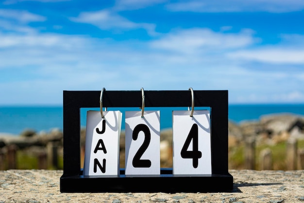 Foto texto della data del calendario del 24 gennaio su una cornice di legno con sfondo sfocato del concetto di calendario oceanico