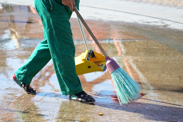 Janitor cleans the sidewalk of the city from fallen leaves