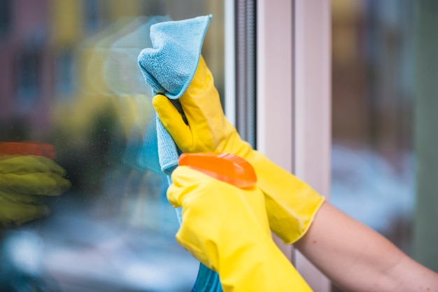 Photo janitor's hand cleaning glass window with cloth