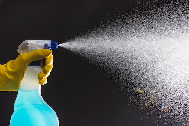 Janitor's hand spraying detergent with spray bottle