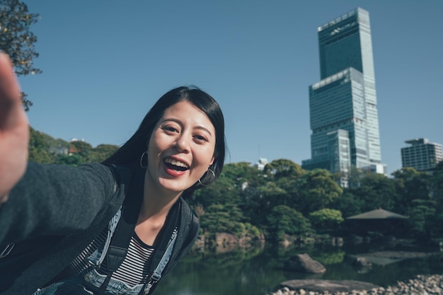 japan reizen Aziatisch meisje toerist selfie foto nemen met de hoogste wolkenkrabber in osaka. Gelukkige chinese jonge vrouw maakt zelfportret lachende gezichtscamera die buiten staat met een tuin in Japanse stijl.