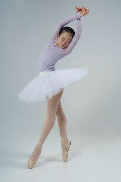 Japanese ballerina poses in a photo studio with ballet elements showing stretching and plasticity