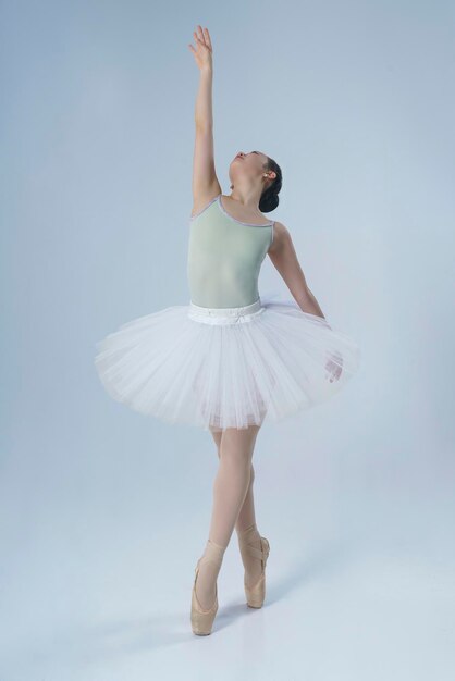 Japanese ballerina poses in a photo studio with ballet elements showing stretching and plasticity