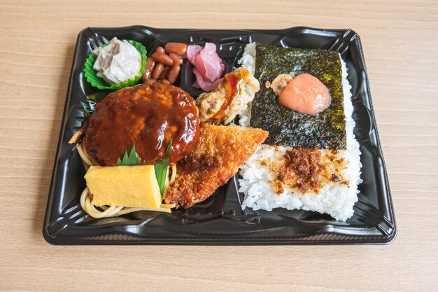 Japanese bento set lunch box of hamburger steak seaweed on rice fried fish and Japanese rolled omelet