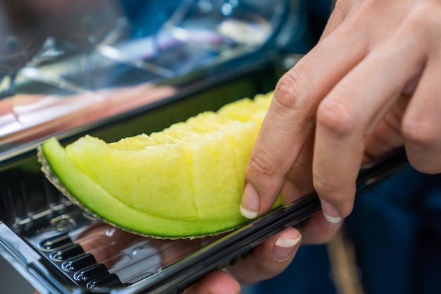 Japanese cantaloupe in plastic bos on women hand, in fish market with foodstreet theme.