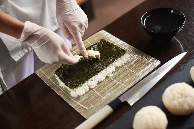 Японский шеф-повар готовит суши в ресторане.