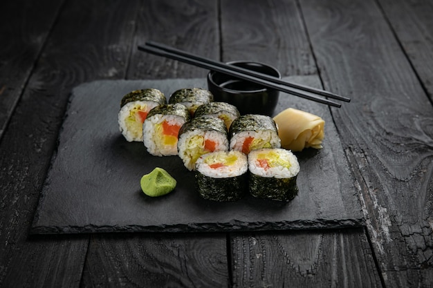 Japanese cuisine Rolls on a square plate on a black table