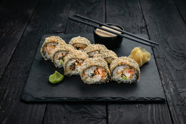 Japanese cuisine Rolls on a square plate on a black table