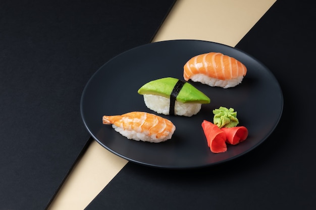 Foto set di cucina giapponese di nigiri sushi con avocado di salmone e gamberetti su una piastra nera