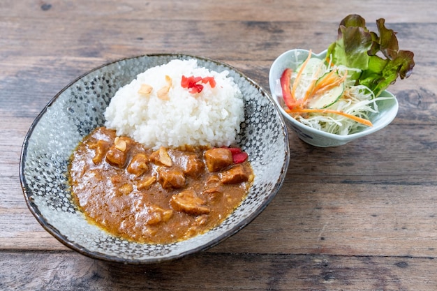 木製の背景に豚肉と日本のカレーライス