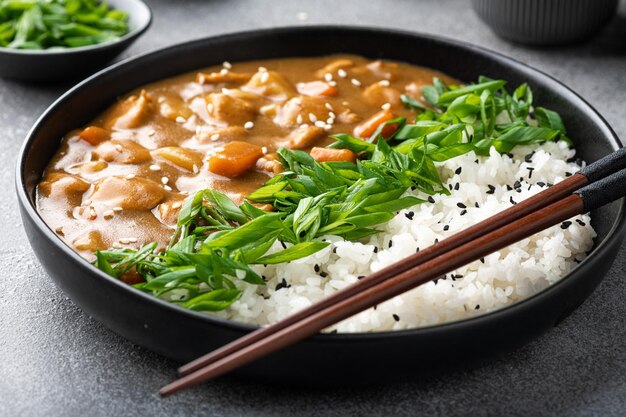 Curry giapponese con riso in un primo piano del fuoco selettivo della piastra di ceramica nera