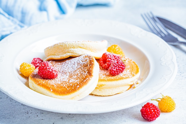 Photo japanese fluffy pancakes with raspberries in a white plate, white background. japanese cuisine concept.