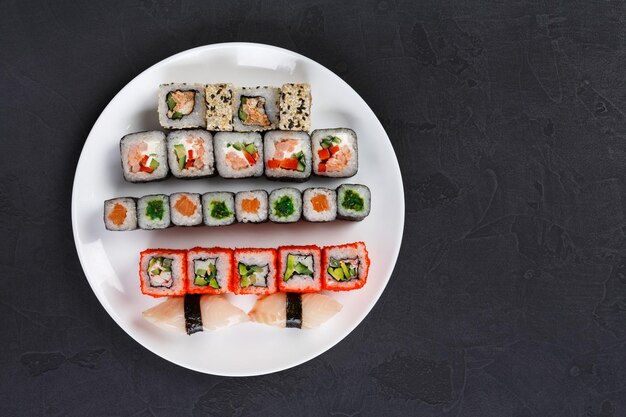 Japanese food restaurant, california salmon rolls and sushi platter. Top view on black background