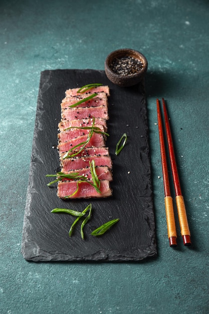 Cibo giapponese tataki di tonno sashimi di tonno crudo searahi con cesamo su tavola nera