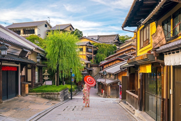 写真 京都の旧市街で赤い傘を持つ浴衣の日本人の女の子